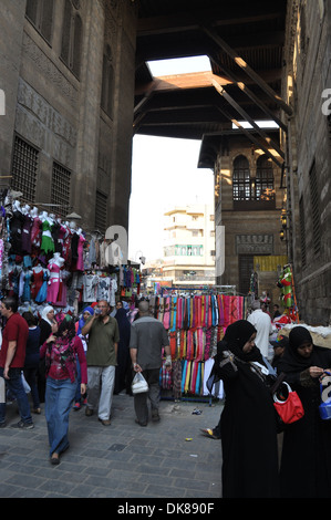 La gente cammina attraverso un mercato dell'abbigliamento nel quartiere islamico della capitale egiziana il Cairo. Foto Stock