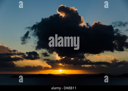 Sun sagome a grandi nuvole appena sopra l'orizzonte durante un bellissimo tramonto dei Caraibi nelle Isole Vergini statunitensi. Foto Stock