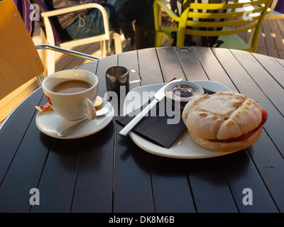 Gustoso pasto di mezzogiorno bacon sandwich con salsa bruna e una tazza di caffè all'aperto presso una caffetteria sul mare in autunno Foto Stock