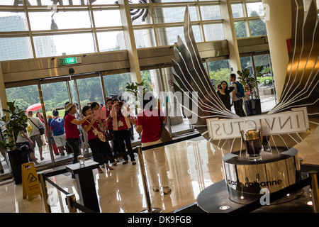 Un gruppo di turisti cinesi di scattare foto nella parte anteriore di un profumo nel display il Suria KLCC Shopping Mall a Kuala Lumpur Foto Stock