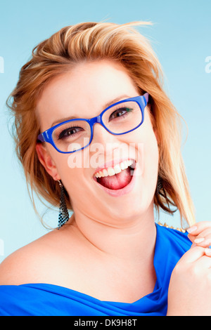 Ritratto di giovane donna con capelli biondi sorridendo - Isolato su blu Foto Stock