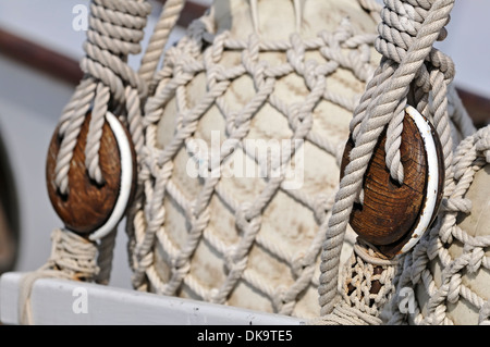 Close-up di vecchi blocchi su di una barca a vela con i paraurti ricoperto di corda net Foto Stock