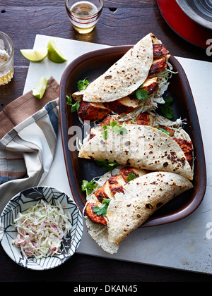Tavolo con piatto di tacos di pollo e erbe aromatiche Foto Stock