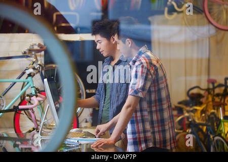 Due giovani uomini in bike shop tramite il computer Foto Stock