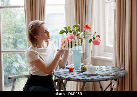 Donna disponendo le rose in vaso Foto Stock