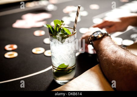 Immagine ritagliata del tavolo da gioco con le carte da gioco, patatine e cocktail Foto Stock