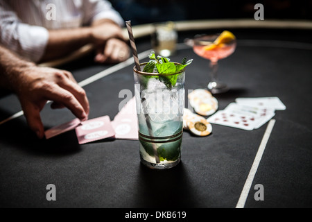 Immagine ritagliata del tavolo da gioco con le carte da gioco, patatine e cocktail Foto Stock