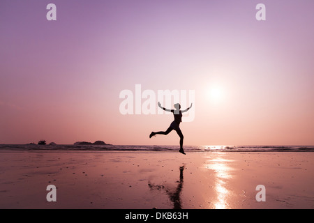 Giovane donna salta sulla spiaggia Foto Stock