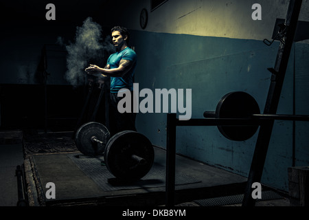 Weightlifter in dark palestra, mettendo chalk sulle mani Foto Stock