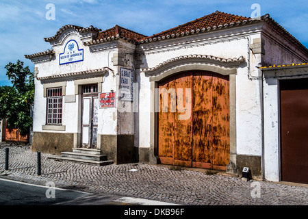 Vecchio edificio con una grande porta di marrone, verniciato di colore bianco sulla strada di ciottoli Foto Stock