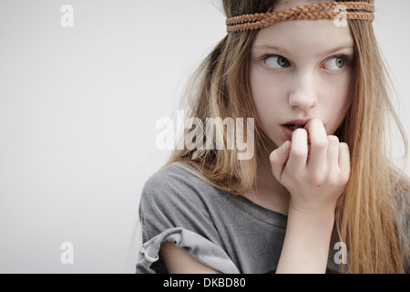 Ritratto di una ragazza che indossa la treccia in pelle attorno alla testa, tenendo giù, il dito in bocca Foto Stock