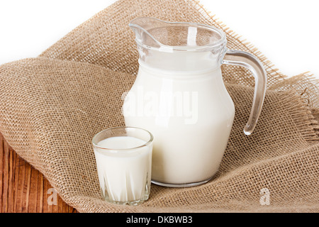 Composizione del latte in un recipiente, un vetro su sfondo di tela Foto Stock