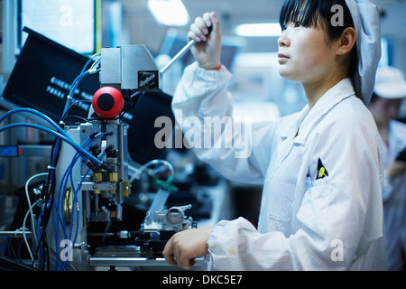 Lavoratore in piccole parti di stabilimento di produzione in Cina Foto Stock