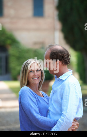 Coppia matura in piedi in giardino avvolgente Foto Stock