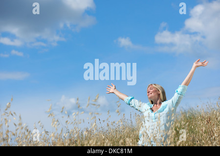 Donna in piedi nel campo di mais con le braccia sollevate Foto Stock