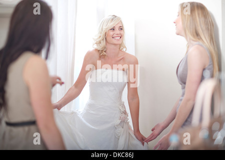 Giovane donna cercando in abito da sposa, con gli amici Foto Stock