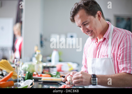 Uomo maturo per la cottura e la preparazione di ingredienti Foto Stock