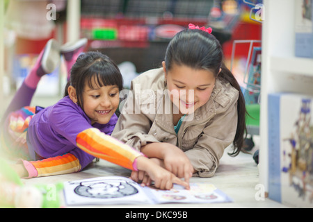 Due sorelle guardando picture book nel negozio di giocattoli Foto Stock