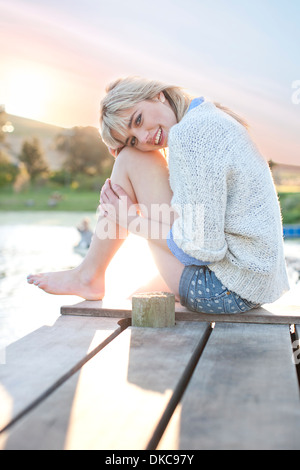 Shy giovane donna seduta sul molo Foto Stock