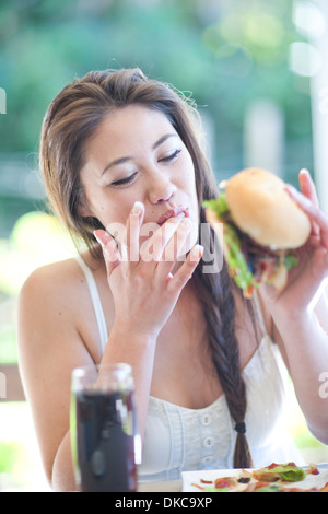 Giovane donna godendo di un burger Foto Stock