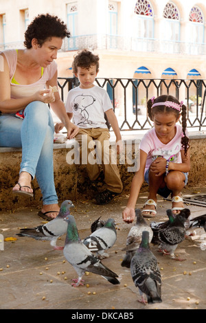 Bambini alimentazione dei piccioni in Piazza Plaza de Armas, Havana, Cuba, Caraibi Foto Stock