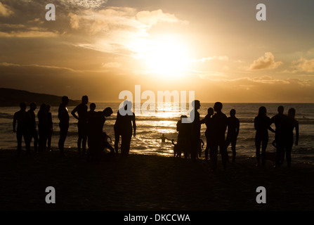 I surfisti e un cane sulla spiaggia di Llandudno al tramonto, Città del Capo Foto Stock