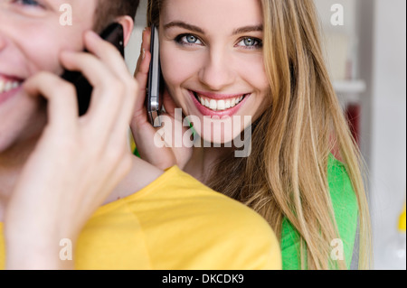 Ragazza adolescente sul telefono cellulare con uomo in primo piano Foto Stock