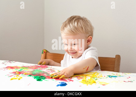 Little Boy giocando con il dito le vernici Foto Stock