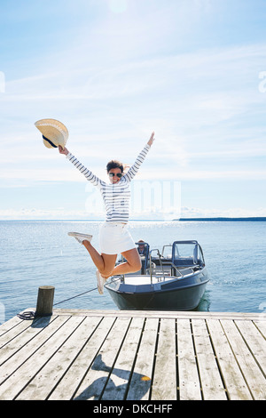 Giovane donna salta in aria intermedia sul molo, Gavle, Svezia Foto Stock