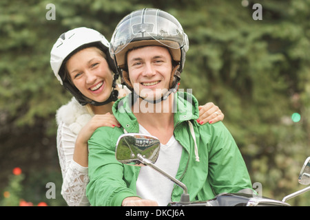 Ritratto di giovane coppia caschi seduto sulla vespa Foto Stock