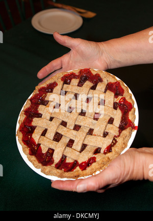 Due mani appena sfornato Torta di ciliegie. Foto Stock