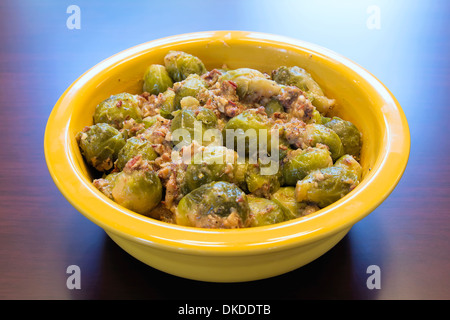 I cavoletti di Bruxelles cotti con pancetta Olio d'oliva e cipolla nel recipiente di colore giallo Foto Stock