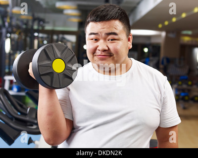 Il sovrappeso giovane uomo che lavora in palestra Foto Stock