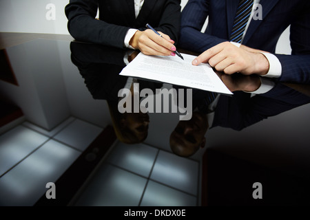 Immagine di mani umane durante la lettura del contratto Foto Stock