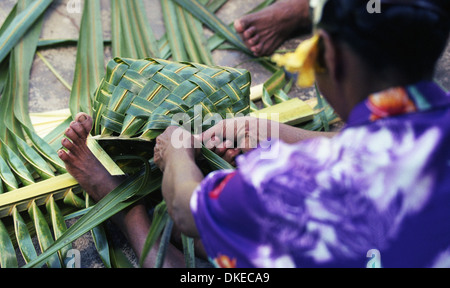 Una donna polinesiana intreccio cesti utilizzando materiali da palme da cocco. Foto Stock