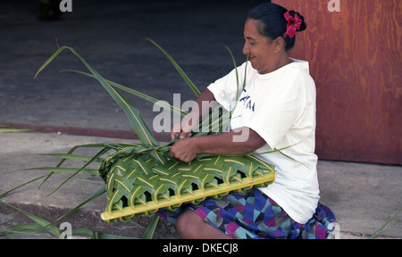 Una donna polinesiana intreccio cesti utilizzando materiali da palme da cocco. Foto Stock