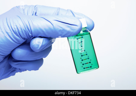 La ricerca in biologia: mano che indossa un guanto in nitrile è in possesso di una fiala con un modello della molecola di DNA all'interno Foto Stock