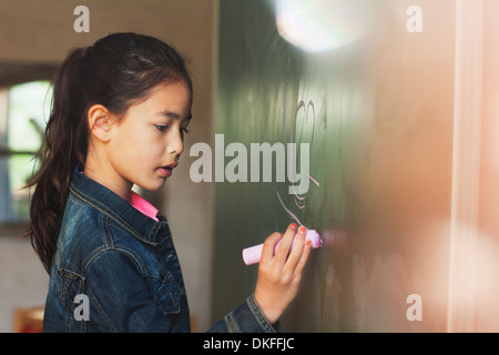 Ragazza la scrittura con gesso sulla lavagna Foto Stock