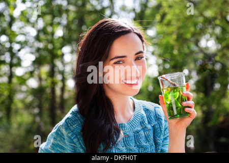 Ritratto di giovane donna in giardino con soft drink Foto Stock