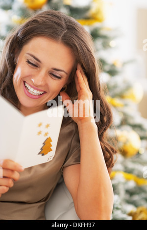 Sorridente giovane donna lettura cartolina di Natale Foto Stock