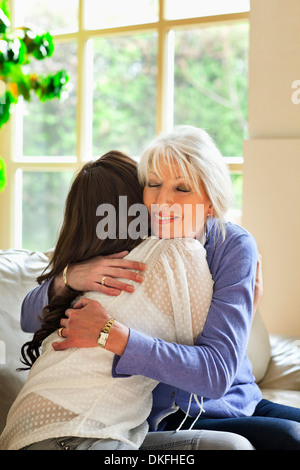 Madre e figlia abbracciando sul divano Foto Stock