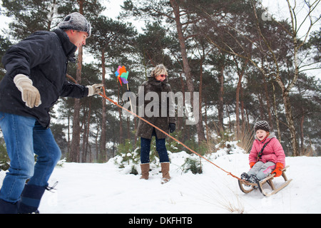 Il padre e la nonna tirando ragazza sul toboga in snow Foto Stock