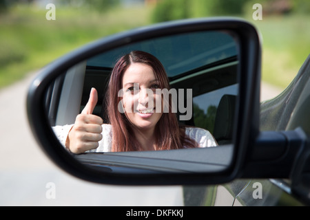 Una felice inclinazione pilota al di fuori della finestra e mostra i pollici fino allo specchio Foto Stock