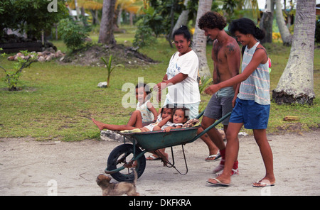 Un padre di trasportare i suoi figli in una carriola in l'isola di Raroia, Polinesia Francese Foto Stock