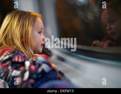 Ragazza guardando fuori della finestra del bus durante un viaggio di notte Foto Stock