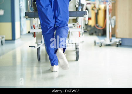 Gambe di medic in esecuzione con barella lungo il corridoio di ospedale Foto Stock