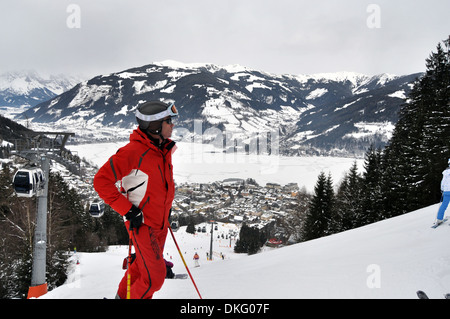 Uomo in un rosso brillante vestito da sci sorge nella parte superiore della pista, Zell am See, Austria Foto Stock