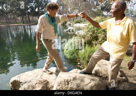 Ritratto di coppia senior intensificazione su rocce dal lago in posizione di parcheggio Foto Stock