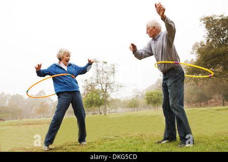 Il marito e la moglie giocando hula hoop nel parco Foto Stock