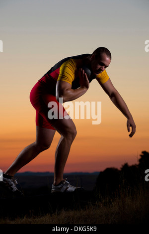 Giovane uomo si prepara a lanciare colpo messo al tramonto Foto Stock